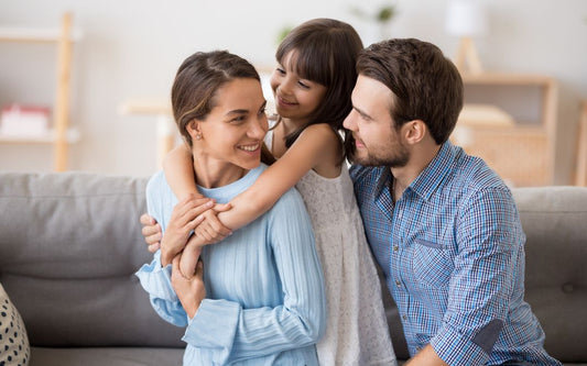 A cozy family moment at home — maybe parents and kids sitting together on a couch, reading or laughing.