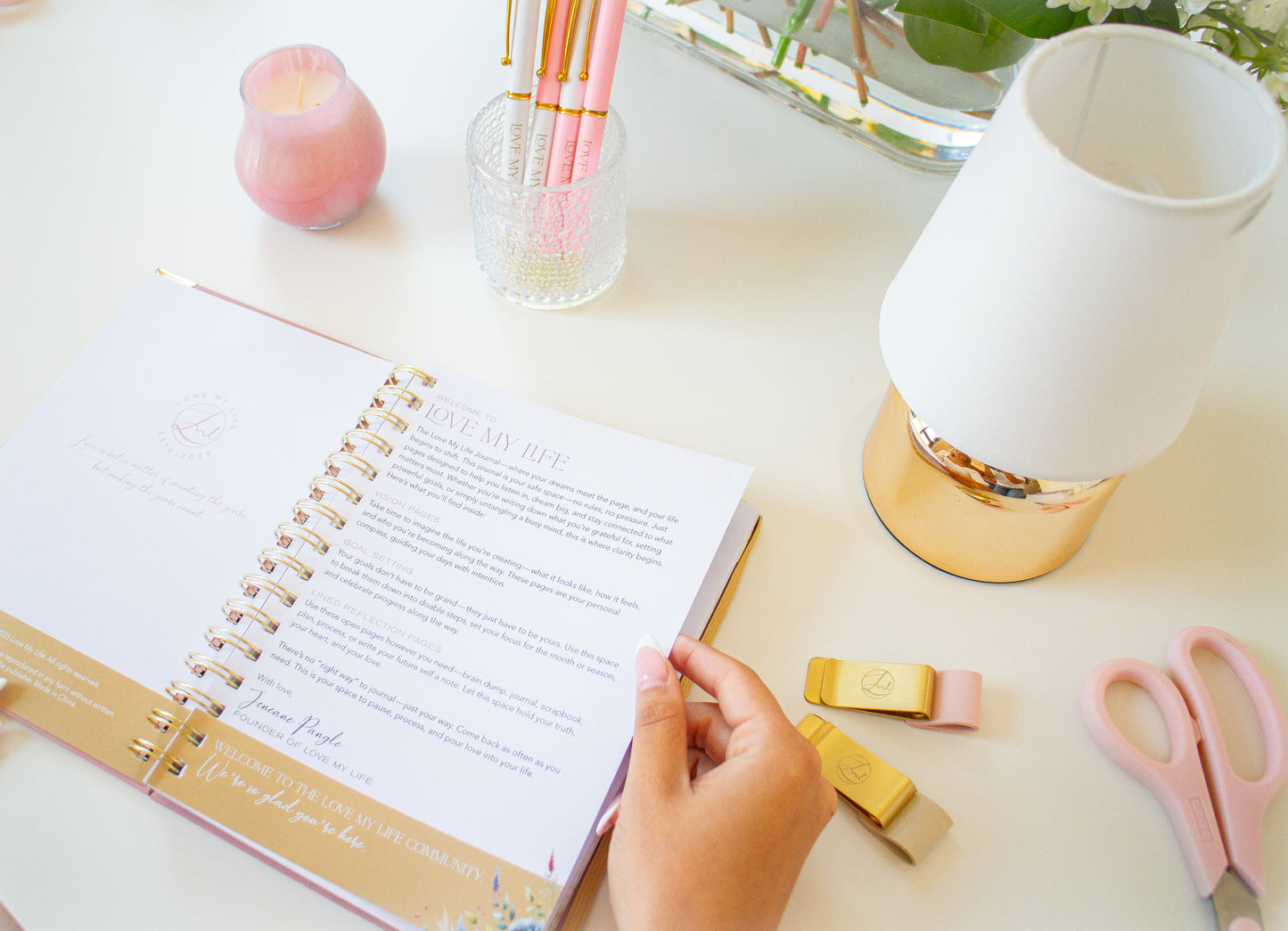 Open planner on a desk with stationery items including scissors and a lamp.
