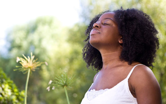 A woman standing in soft natural light, looking peaceful and grounded 