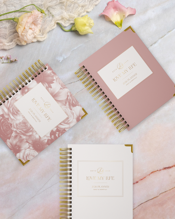 Three spiral-bound planners with floral designs on a marble surface.