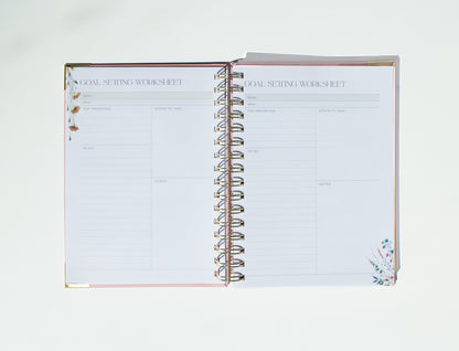 Open spiral-bound notebook with 'Goal Setting Worksheet' on a white background