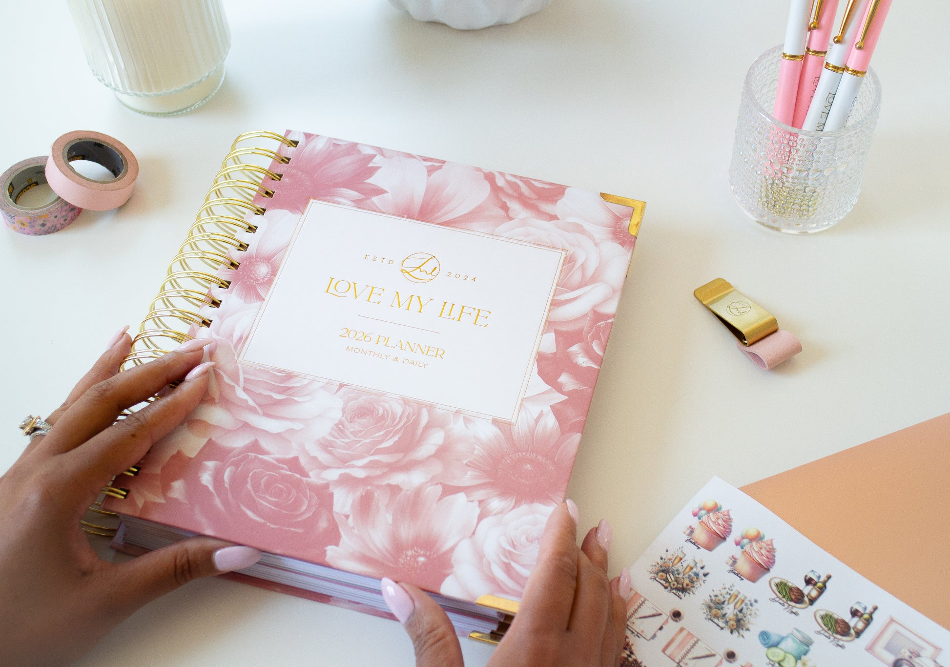 Pink floral planner on a desk with stationery items