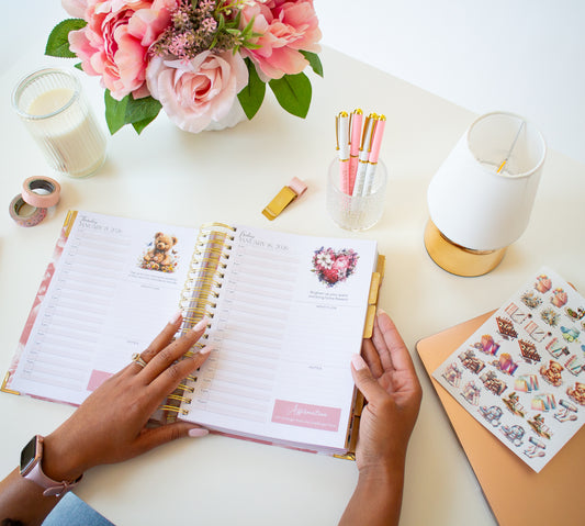 Person using a planner with stationery items on a desk