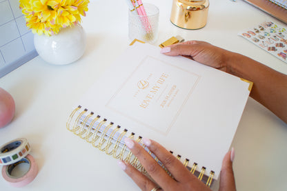 Person holding a planner with decorative items on a desk