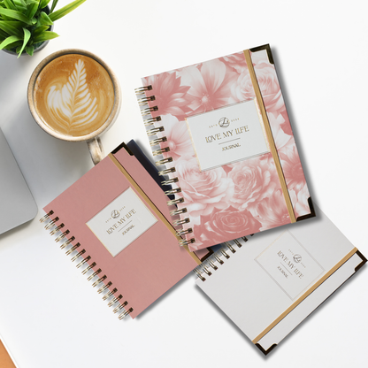 Three notebooks with floral design and 'Love My Life' branding on a white surface with a cup of coffee.